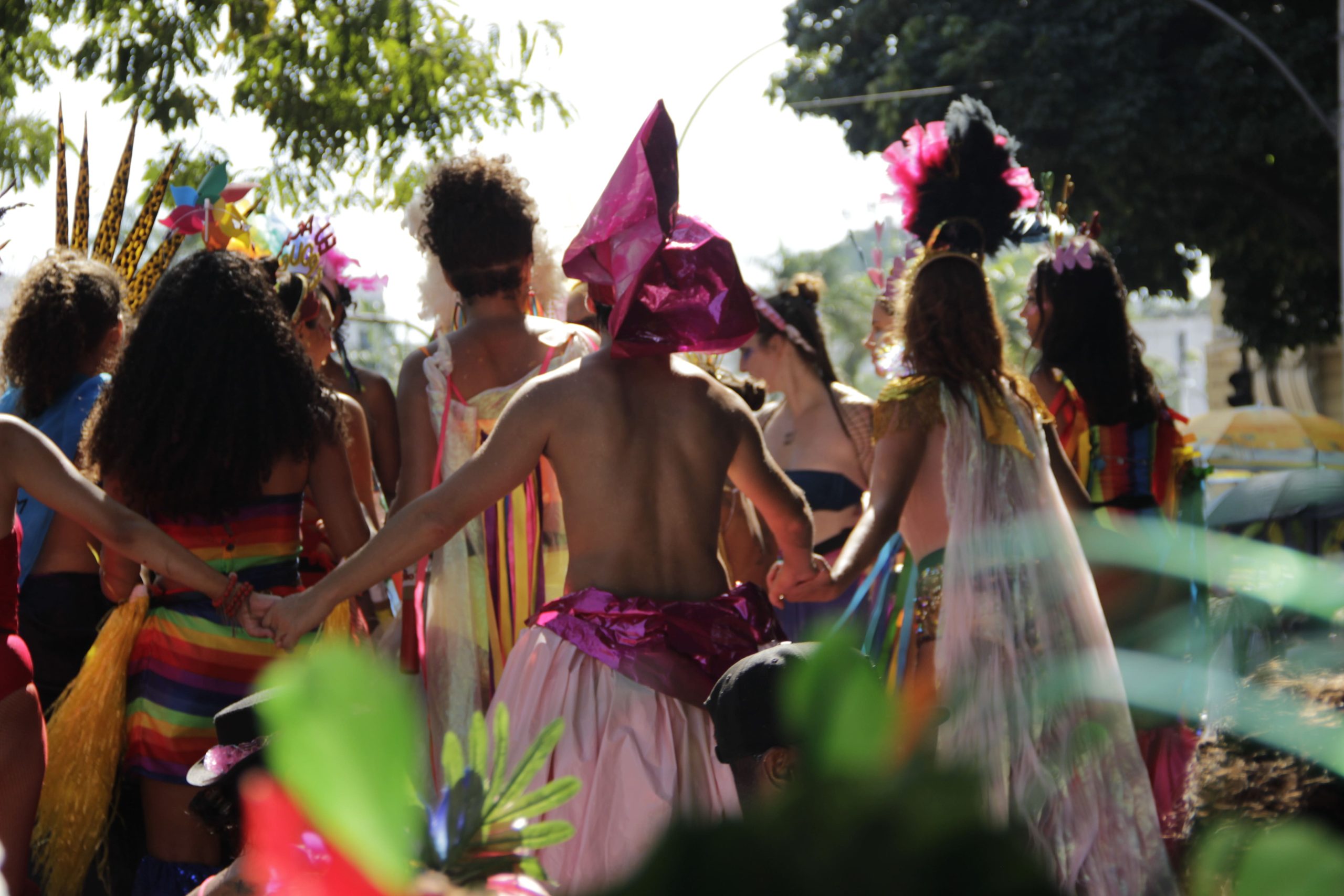 Danseurs vêtus de costumes colorés et de coiffes festives, tenant les mains pour former un cercle lors d’un carnaval