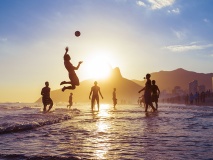 sunset silhouettes playing keepy-uppie beach football on the sea shore in Ipanema Beach Rio de Janeiro Brazil